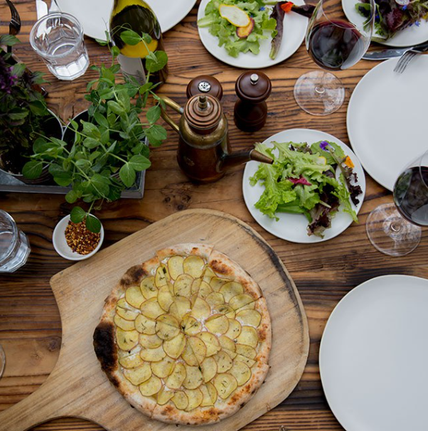 A table covered in SIMI wines, pizza from our wood-fired pizza oven and salads.
